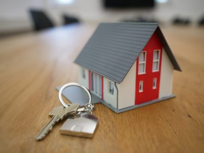 a photo of a house key lying on a table beside a miniature model house